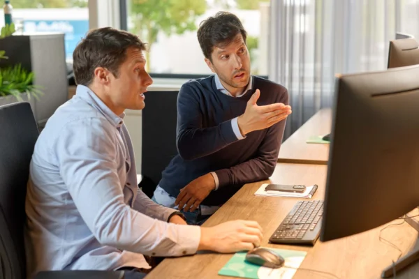 Twee collega's bespreken IT hardware oplossingen terwijl ze naar een computerscherm kijken