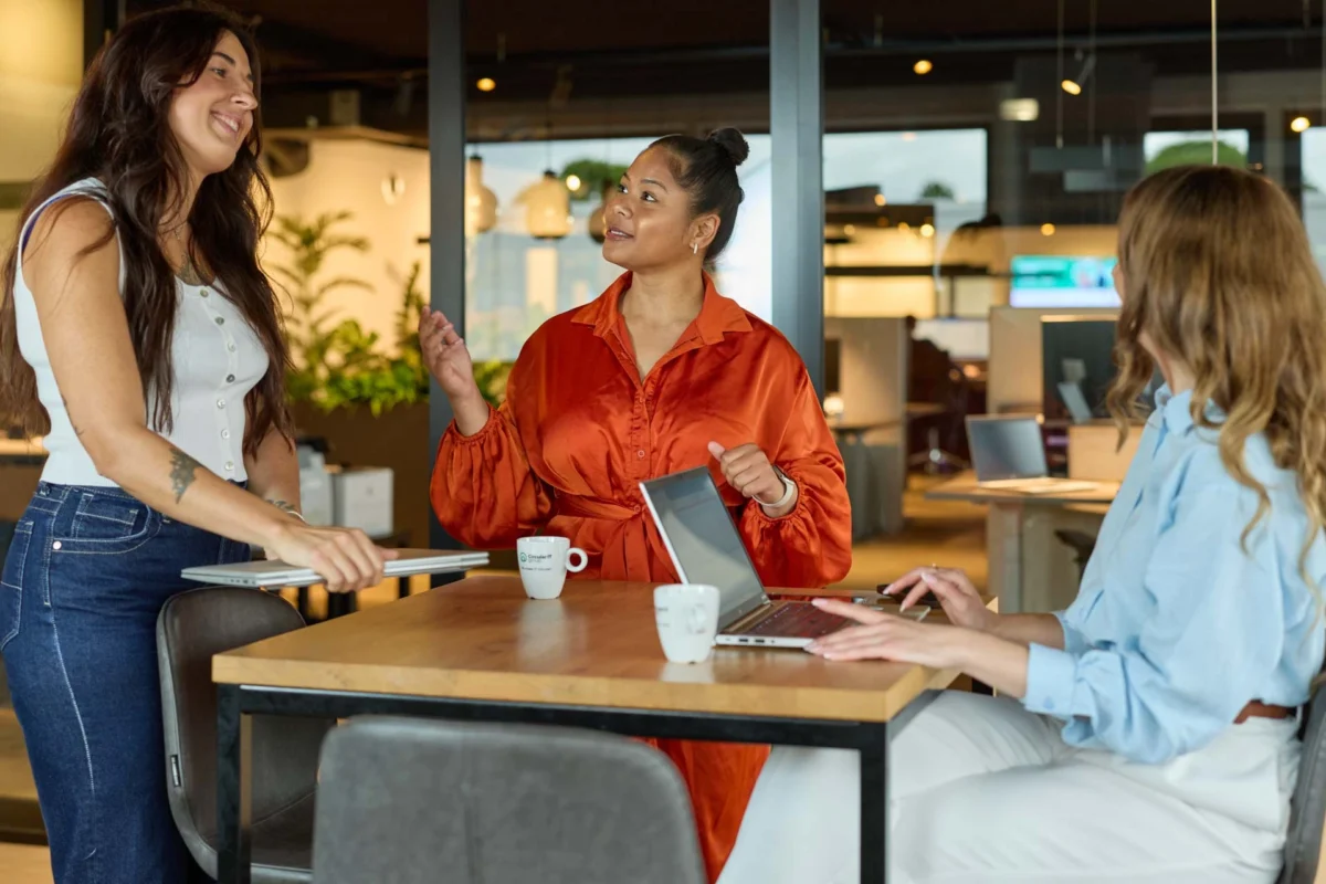 Drie collega's werken samen en bespreken IT oplossingen rond een laptop op kantoor